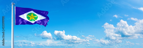 Mato Grosso - state of Brazil, flag waving on a blue sky in beautiful clouds - Horizontal banner photo