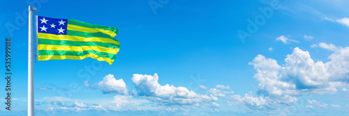 Goiás - state of Brazil, flag waving on a blue sky in beautiful clouds - Horizontal banner