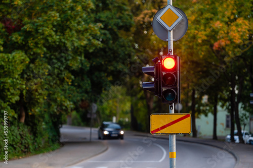 traffic semaphore with red light on defocused background of autumn city, closeup