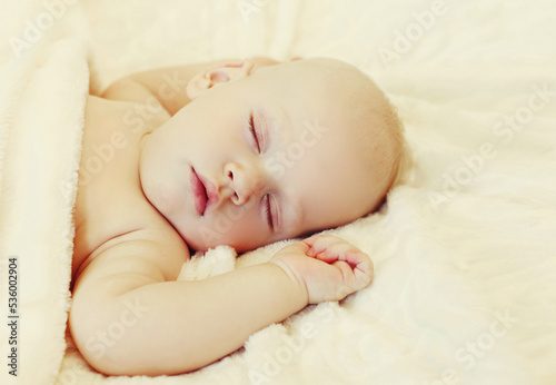 Close up portrait of sweet baby sleeping on a white bed at home © rohappy