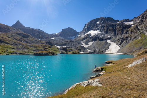 The girl sits against the backdrop of mountain peaks and a blue lake. Beautiful mountain landscape for vacation, travel and healthy lifestyle