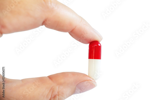 Close up of a hand holding a white and red pill,isolated on trasparent background. Health and medication concept