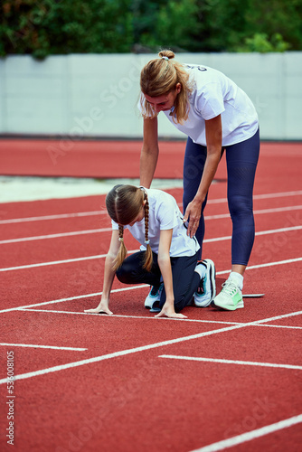 Female coach training athlete. Fit girl getting ready to run on treadmill at the stadium. Concept of sport, achievements, studying, goals, skills. Little teen girl training outdoor.