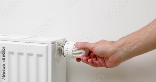 The man turns off the heating by setting the thermostat photo