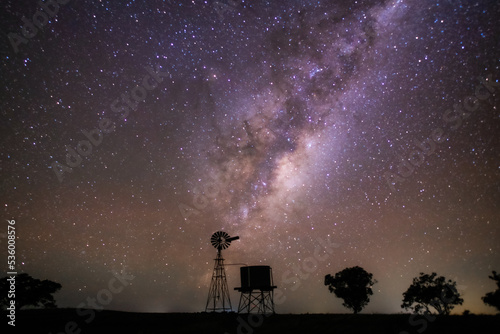 Milky Way rising over a windmill silhouette in a rural setting