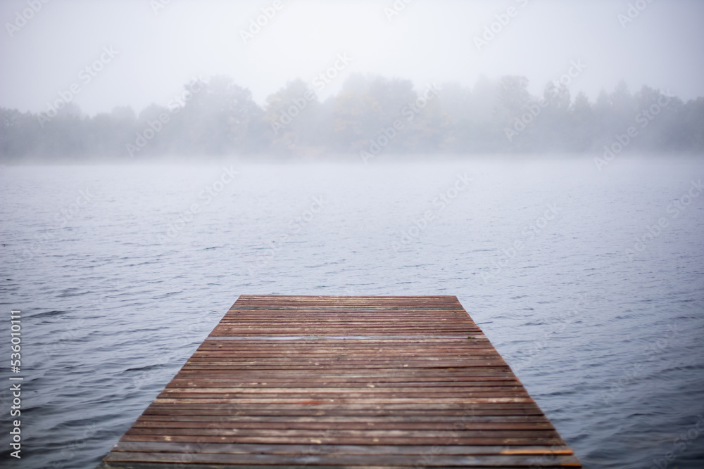 wooden pier pier in the fog on the lake in autumn.