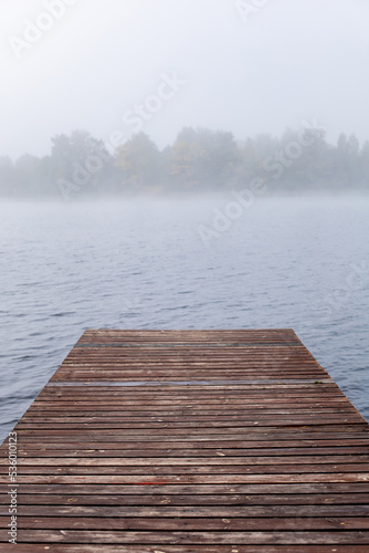 wooden pier pier in the fog on the lake in autumn.