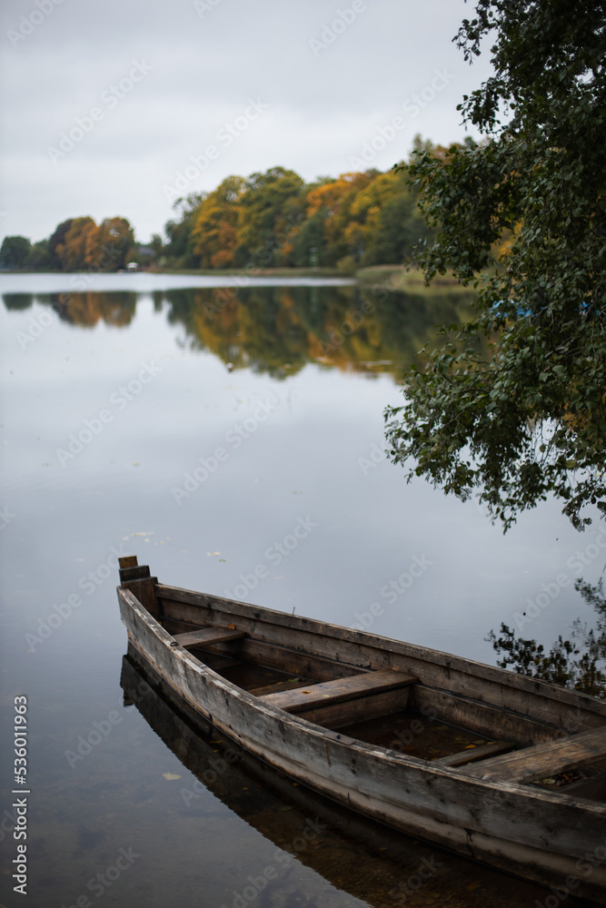 old wooden fishing boat stands on the lake in the village of autumn in cloudy weather.