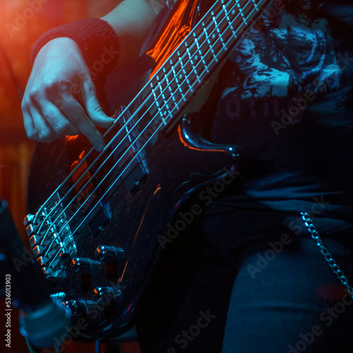 The bass guitarist plays the bass guitar. Dark key. Selective focus