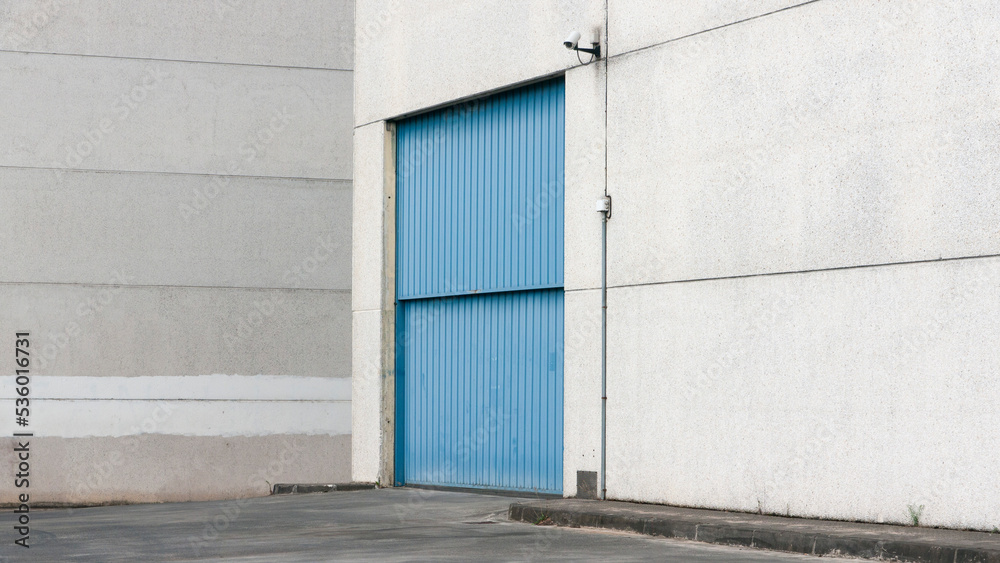 Fototapeta premium Puerta metálica azul en nave industrial de hormigón 