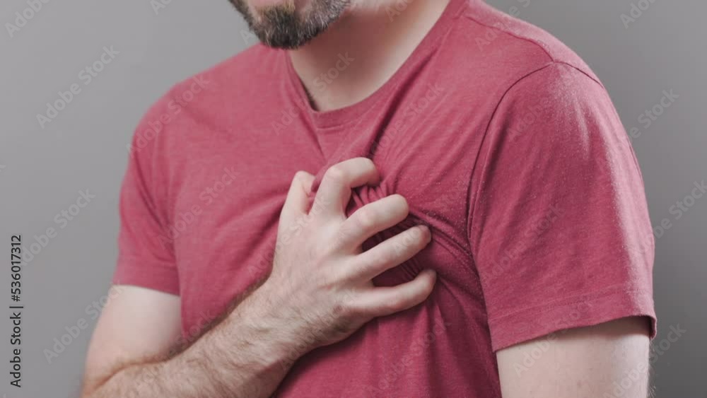 A bearded bald man grabs his chest with his hand, experiencing severe pain. Lung disease. Close up. The concept of a heart attack.
