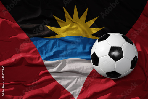 vintage football ball on the waveing national flag of antigua and barbuda background. 3D illustration
