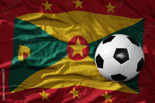 vintage football ball on the waveing national flag of grenada background. 3D illustration
