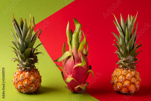 Baby pineapple, pitaya, pitahaya, dragon fruit on tomato and green abstract background. © Show_low