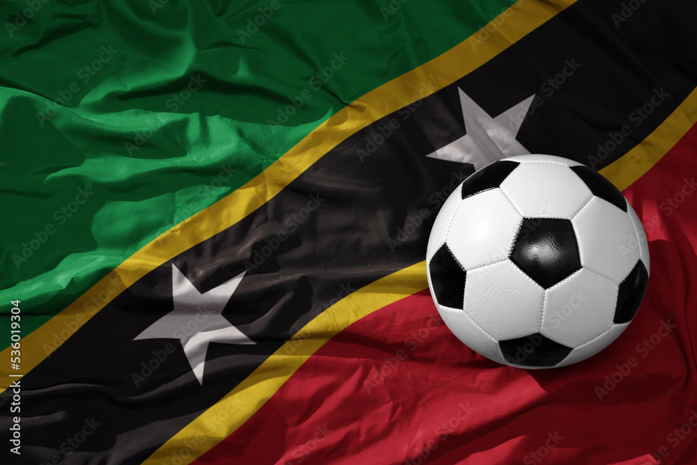 Naklejka premium vintage football ball on the waveing national flag of saint kitts and nevis background. 3D illustration