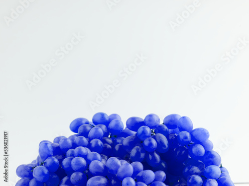 Grapes tinted bright blue on a white background. Lots of space for text