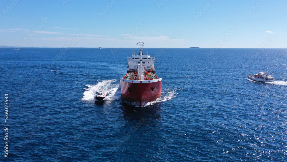 Aerial drone photo of pilot boat and huge crude oil tanker cruising in open ocean deep blue sea Aerial drone photo of pilot boat and huge crude oil tanker cruising in open ocean deep blue sea