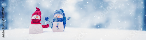 Fotografia Little knitted snowmen on the white snow on blue background.