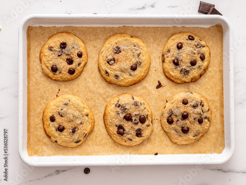 Homemade fresh from the oven on a white metal baking tray American chocolate chip cookies, top view horizontal 