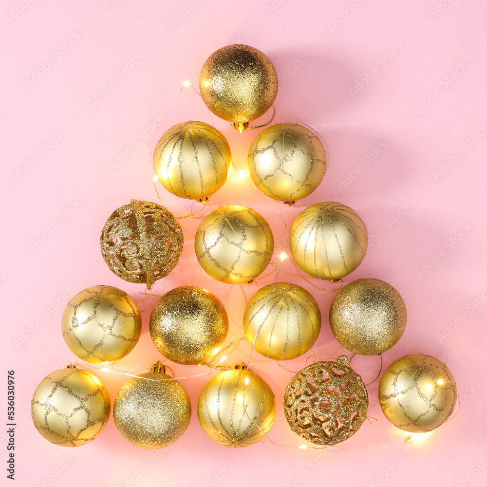 Golden ornaments make Chrismtas tree shape on pastel pink background. Flat lay Golden ornaments make Chrismtas tree shape on pastel pink background. Flat lay