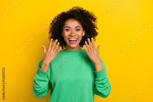 Photo of impressed funky woman wear green pullover smiling rising arms isolated yellow color background