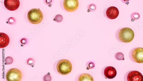 Creative Christmas and new year pattern with gold, red and pink ornaments on pink background with copy space. FLat lay