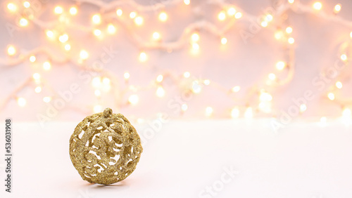 Glitter golden ornament Christmas ball on white background with decorativelights