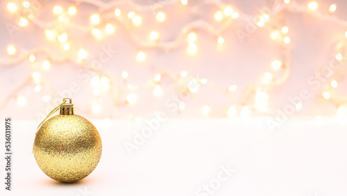 Glitter golden ornament Christmas ball on white background with decorativelights