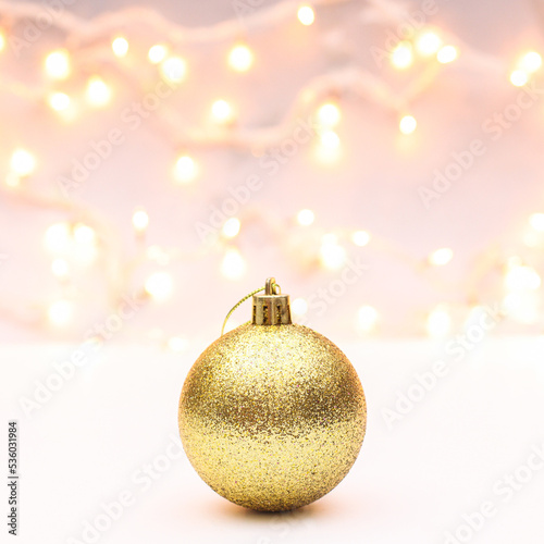Glitter golden ornament Christmas ball on white background with decorativelights