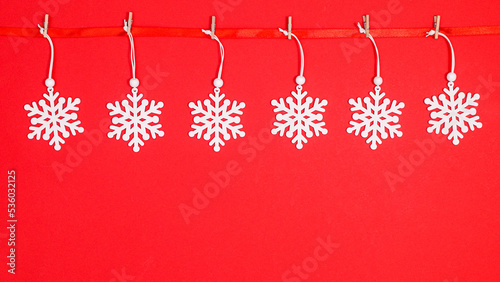 Snow flakes hanged on ribbon garland on red background. FLat lay