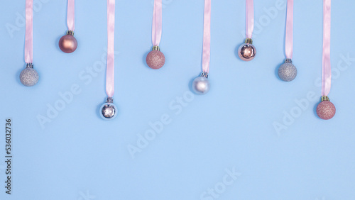 Christmas balls hanged on ribbons on pastel blue background with copy space. Flat lay