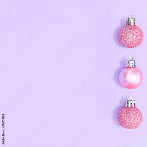 Pastel pink Christmas ornaments on pastel purple background with copy space. FLat lay