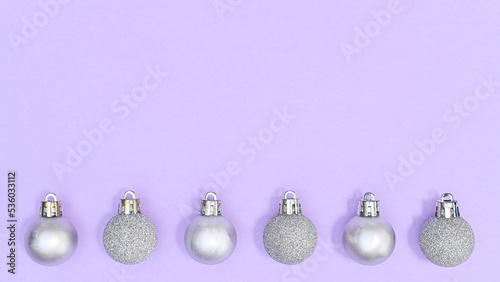 Silver Christmas ornaments on pastel purple background with copy space. FLat lay