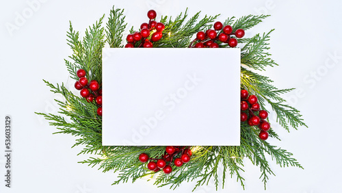 Copy space white paper surrounded with fir frame and red berries on white background. Flat lay