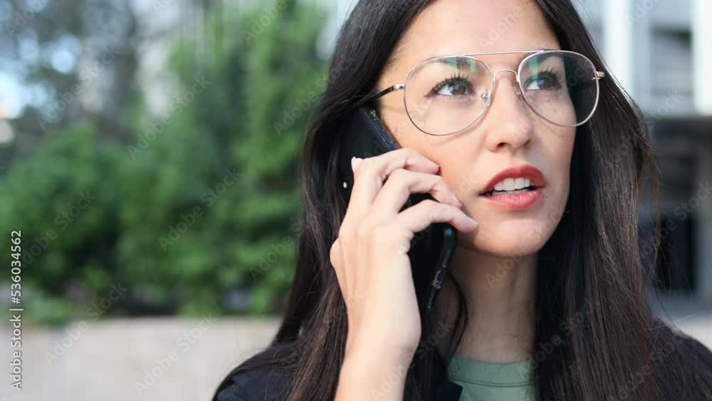 Close-up of a Latin business woman with glasses talking on the cell phone. Close-up of a Latin business woman with glasses talking on the cell phone.