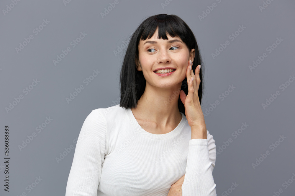 a calm woman stands against a dark background in a tight white T-shirt, throwing her head to the side, touching her neck with her fingers a calm woman stands against a dark background in a tight white T-shirt, throwing her head to the side, touching her neck with her fingers