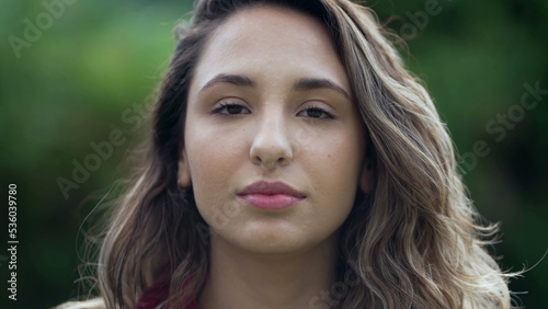 Portrait of a young hispanic woman looking at camera. Casual South American latina girl face closeup standing outdoors at park 2