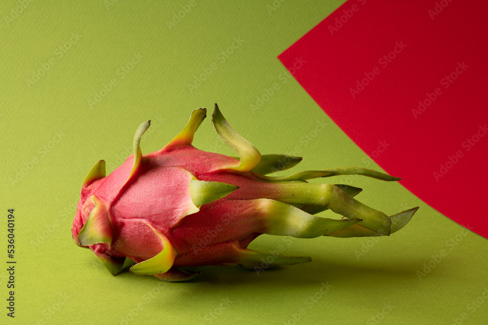 Dragon fruit pitaya, whole pitahaya on green and tomato background. Abstract composition. Dragon fruit pitaya, whole pitahaya on green and tomato background. Abstract composition.