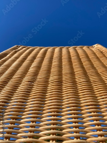 a tapered woven rattan pattern against a blue sky