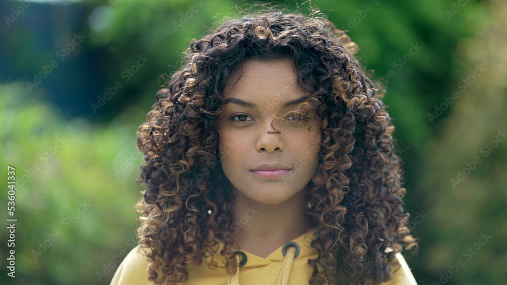 Portrait face closeup of a Brazilian black young woman with curly hair looking at camera. African American hispanic latin girl standing outdoors Portrait face closeup of a Brazilian black young woman with curly hair looking at camera. African American hispanic latin girl standing outdoors
