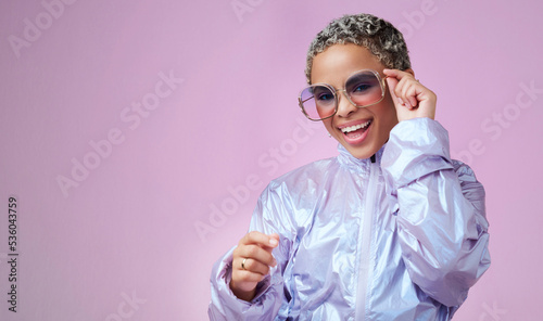Edgy fashion, trendy and black woman with sunglasses in a studio with mockup space. Stylish, creative and portrait of an african girl influencer or model standing by a bright purple background. photo