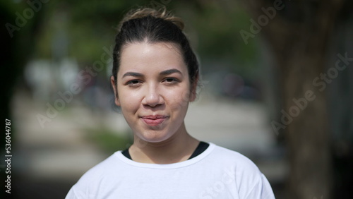 Happy young woman portrait face closeup standing outside looking at camera. Casual female person in 20s stands outdoors © Marco