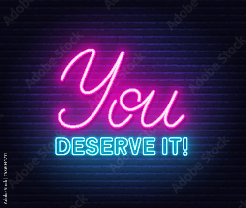 You Deserve It neon quote on a brick wall.