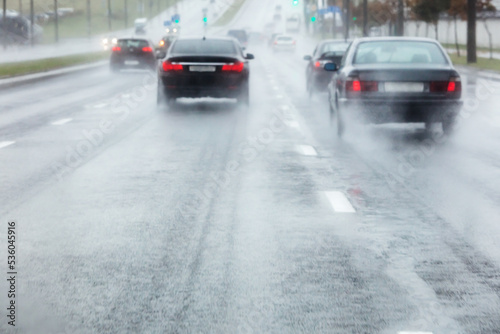 cars rides in wet road with water spraying from the wheels. blurred view through windshield.