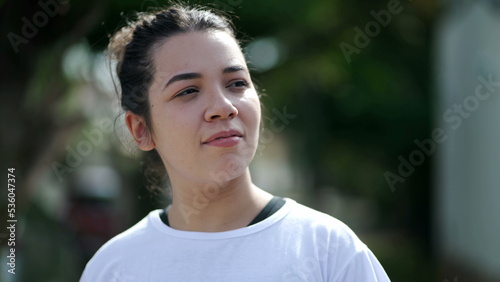 A casual Brazilian girl walking in city street. One pensive 20s woman walks in slow motion outdoors