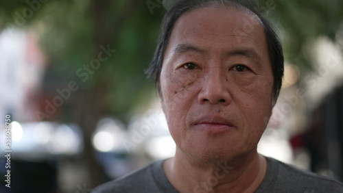 Portrait of an Asian American older man looking at camera. Closeup face of a middle aged Japanese male person