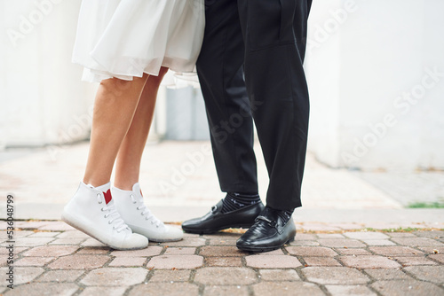 Close up view of legs on the ground. Beautiful bride with his fiance is celebrating wedding outdoors