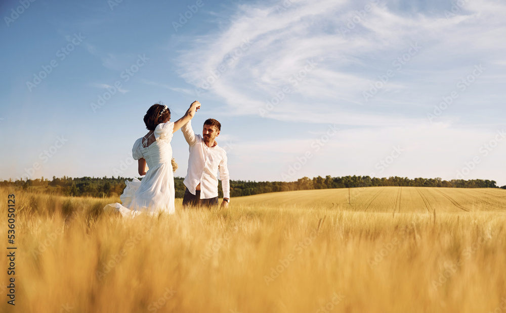 In dress and formal clothes. Couple just married. Together on the majestic agricultural field at sunny day In dress and formal clothes. Couple just married. Together on the majestic agricultural field at sunny day