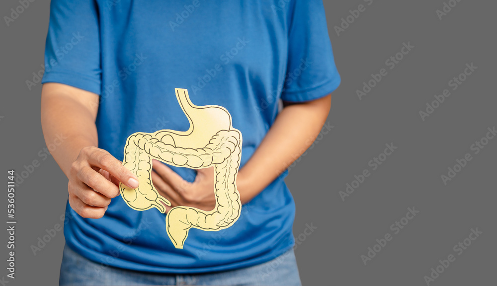 Φωτογραφία Close-up of hands holding a colon symbol and touching stomach painful suffering