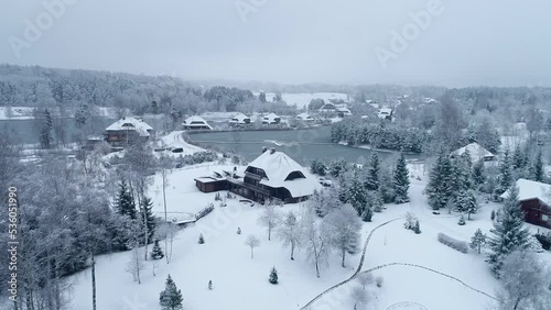Aerial View of Winter in Baltic Countryside Village, Snow Capped Homes and Frozen Lake, Drone Shot photo